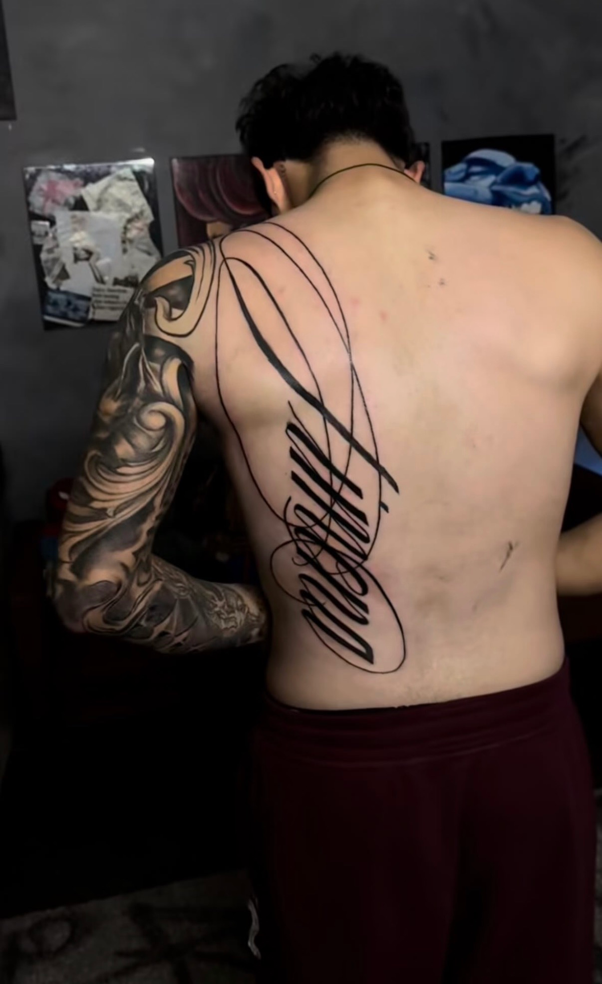 Freehand script lettering tattoo across the full back