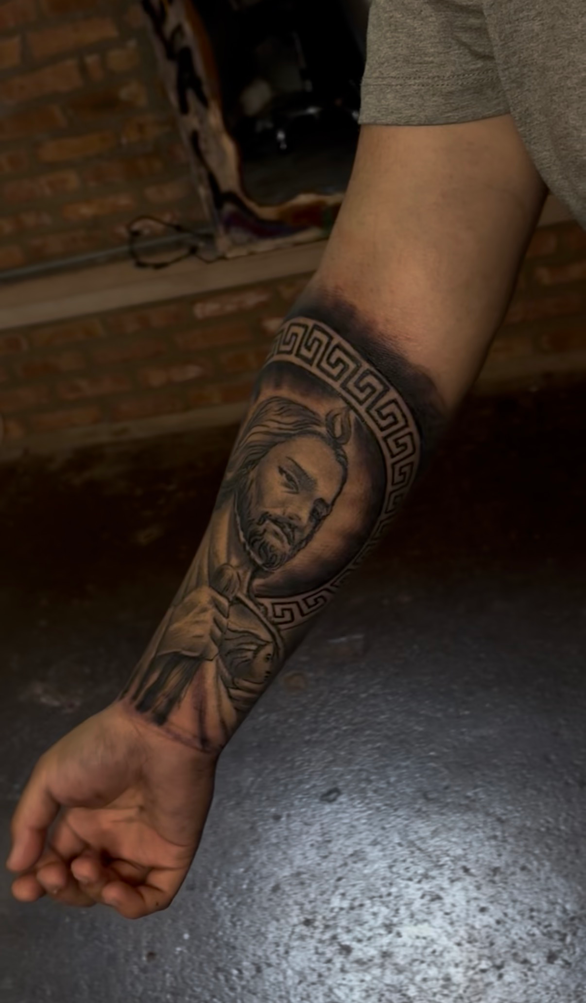 San Judas with greek key border forearm tattoo